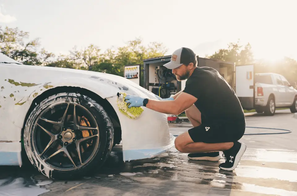 Tanner, owner of Texas Automotive Care Solutions, hand-washing a white sports car in Boerne, TX